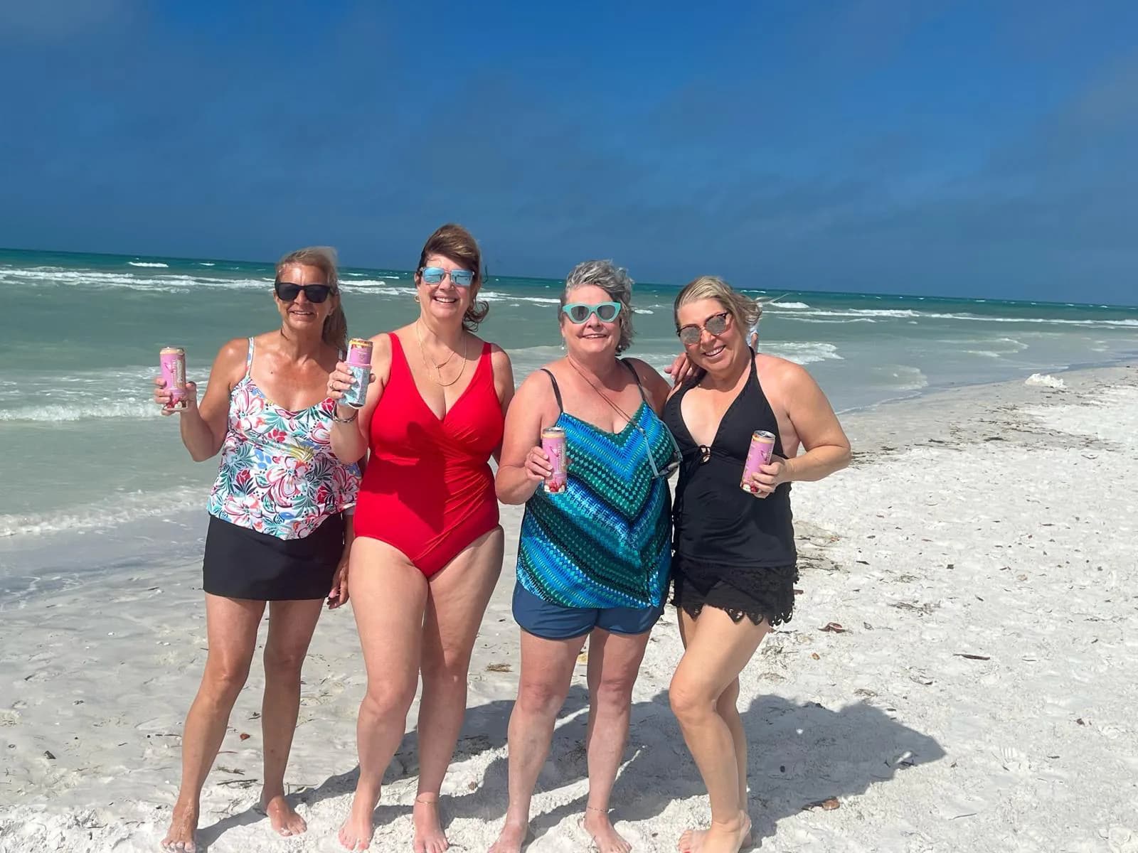 Four women on a sunny beach with ePleazze cans