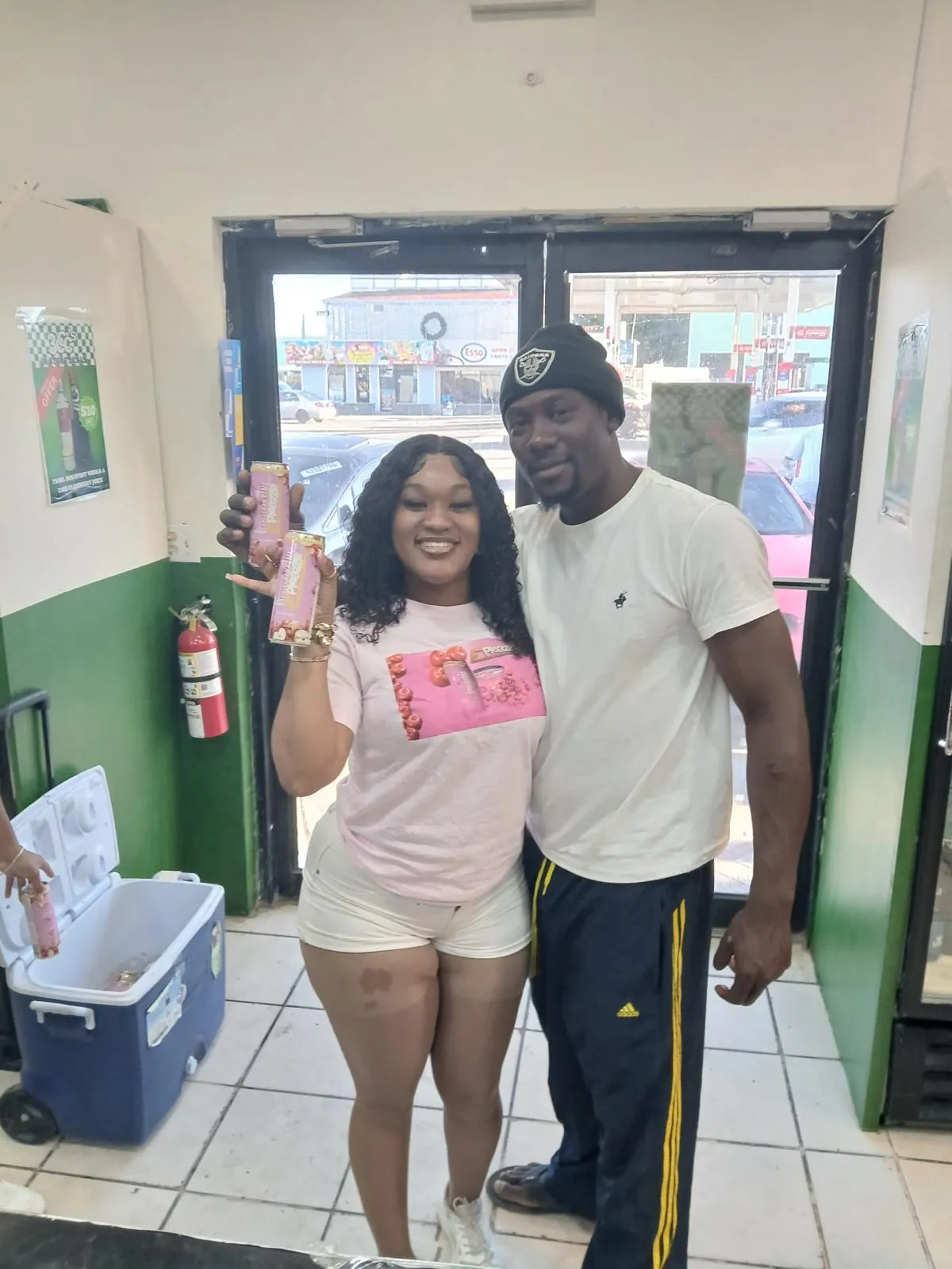 Couple holding ePleazze cans at a Nassau corner store